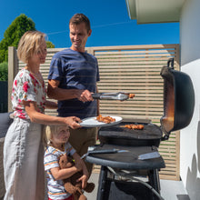 Load image into Gallery viewer, Family barbecuing in front of trellis
